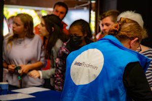 Guests arriving at an event with a volunteer wearing a blue intoBodmin high viz jacket signing people in.